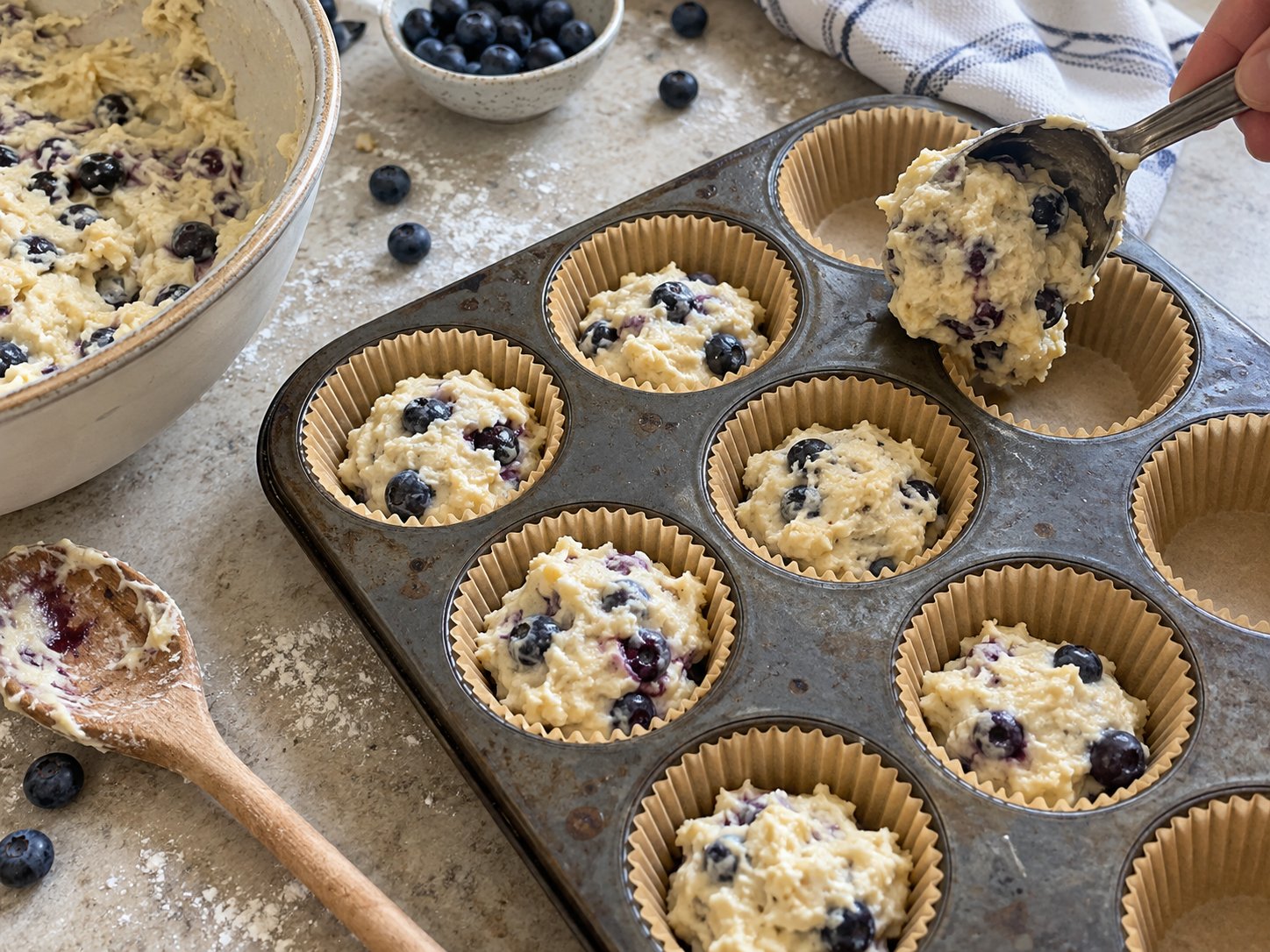 Blueberry muffin batter with fresh berries portioned into a lined muffin pan