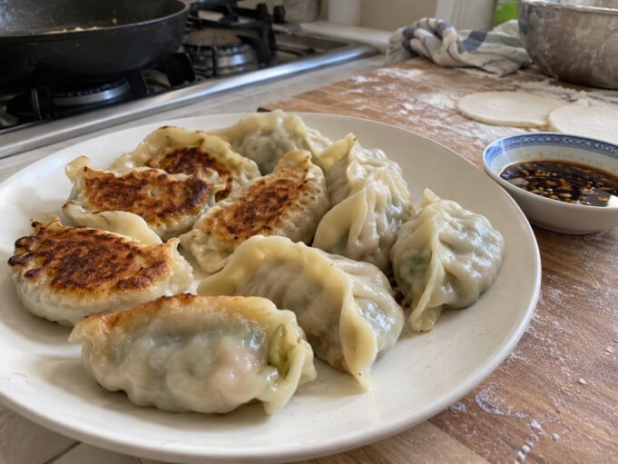 Homemade pork and cabbage jiaozi with golden pan-fried bottoms and soy dipping sauce