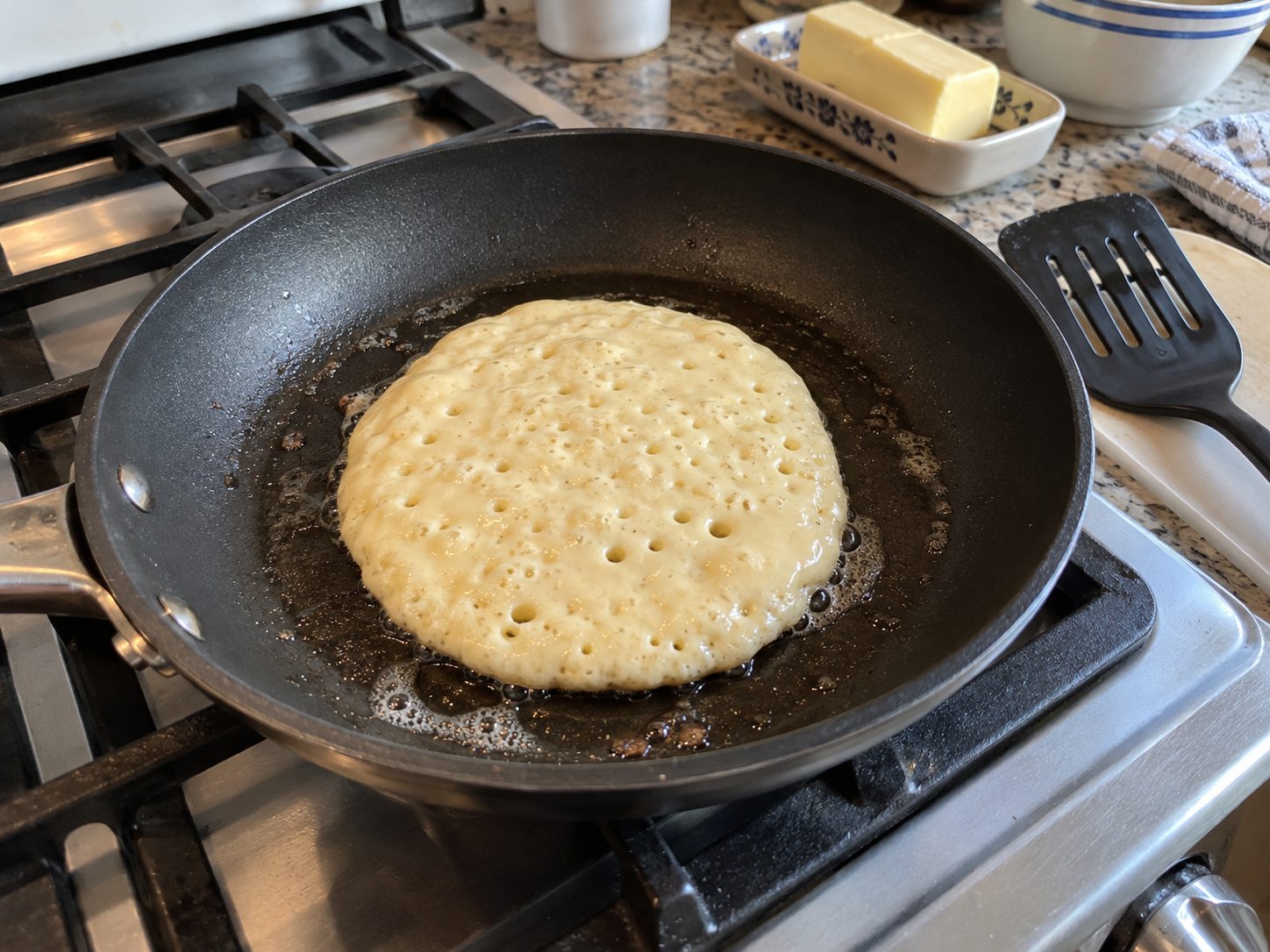 Golden buttermilk pancakes cooking in a lightly greased skillet